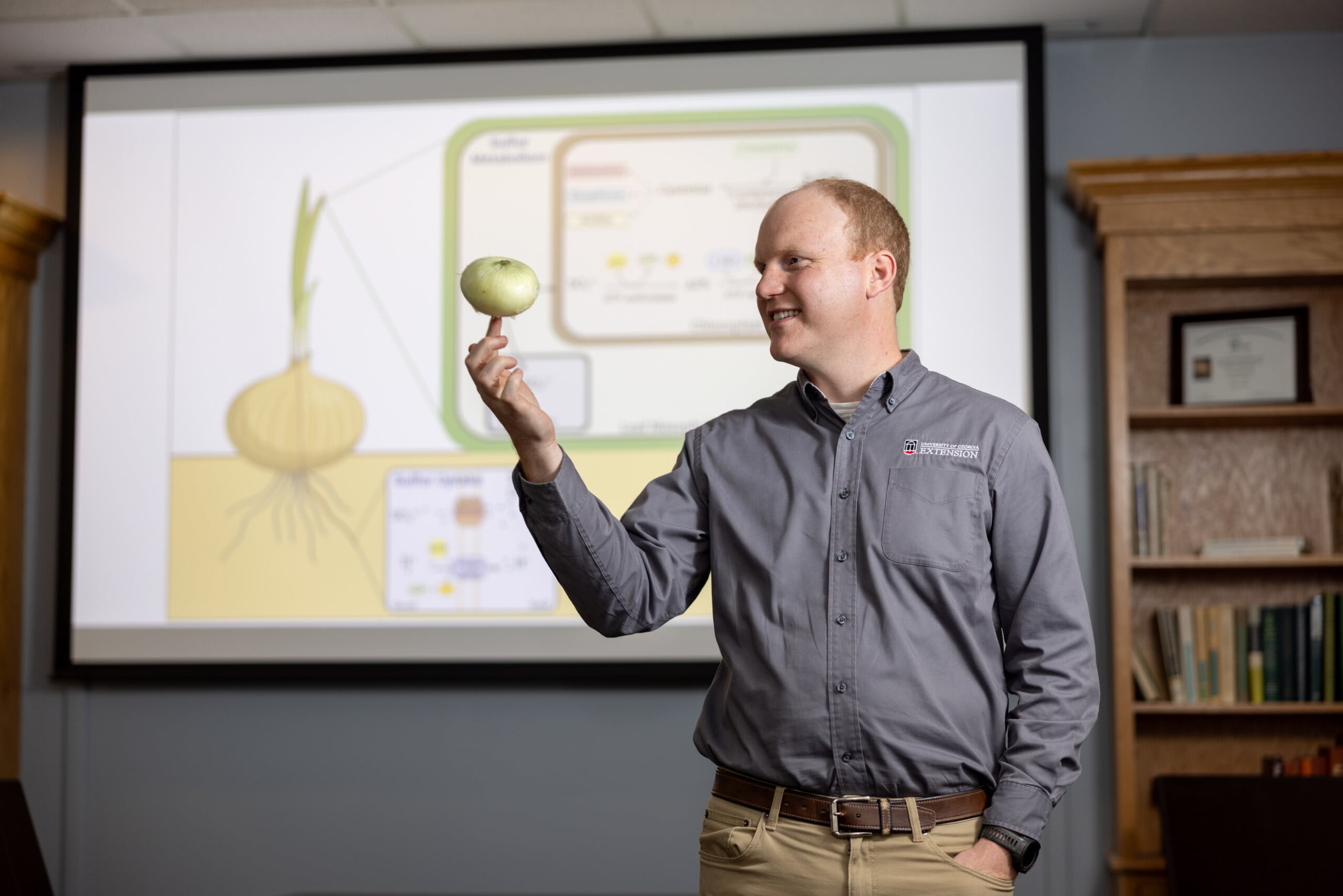 Daniel Jackson balances onion on his finger tip in front of projection of onion diagram