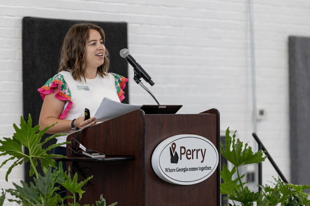 Kaytlyn Cobb speaks at an event. A sign on the podium reads "Perry, where Georgia comes together."