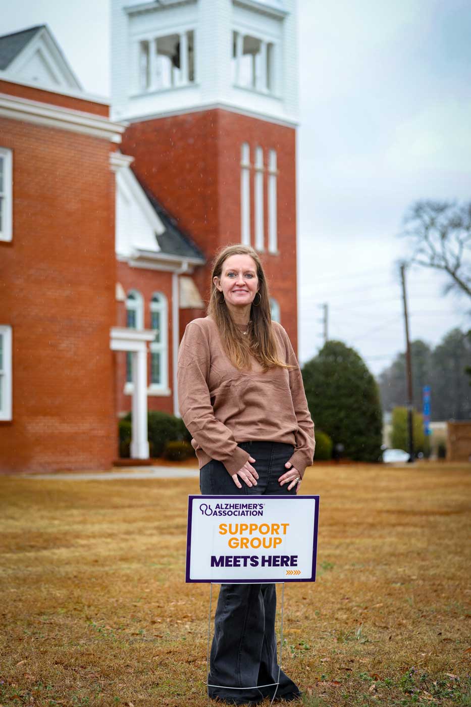 Allison Eaddy stands in front of a church next to sign that says Alzheimers Association Support Group Meets Here