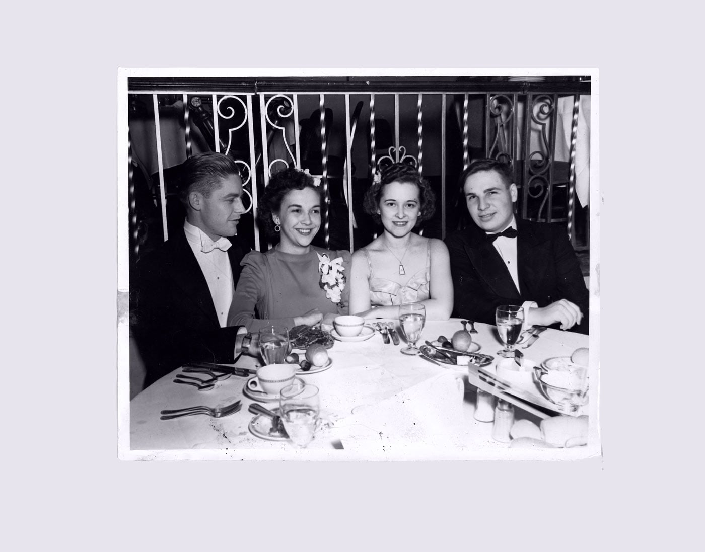 Vintage photo of two young couples in formal wear at a banquet table, circa 1950s