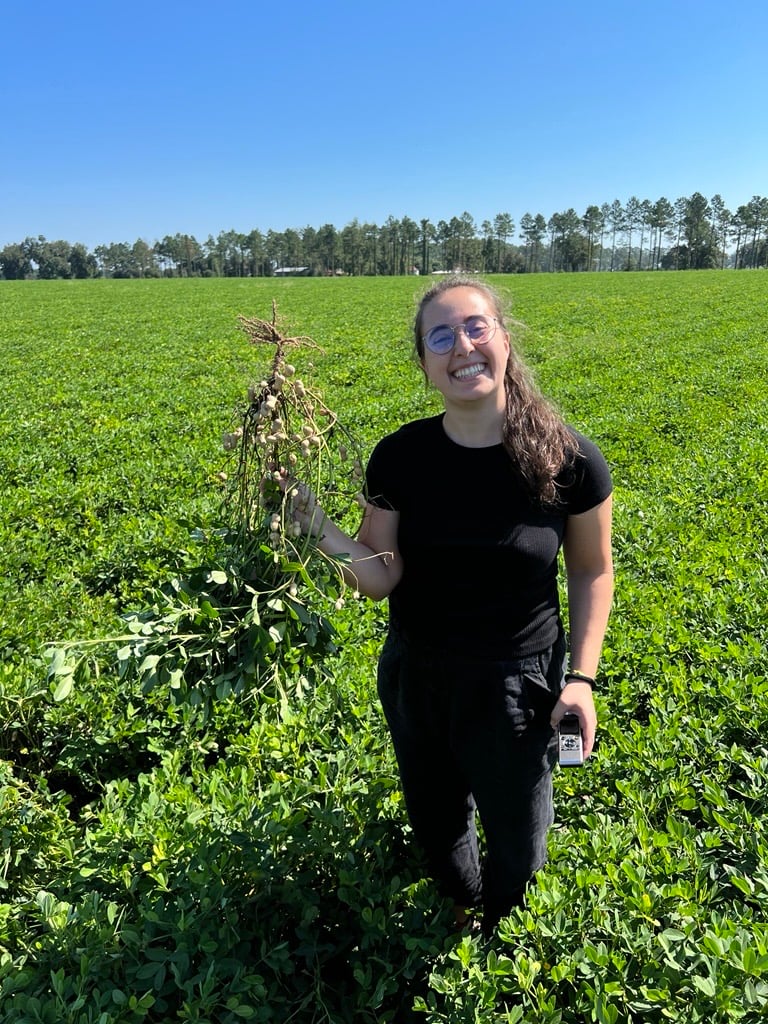 Maria Tancredi stands in a field of crops and holds peanuts freshly pulled from the soil. 