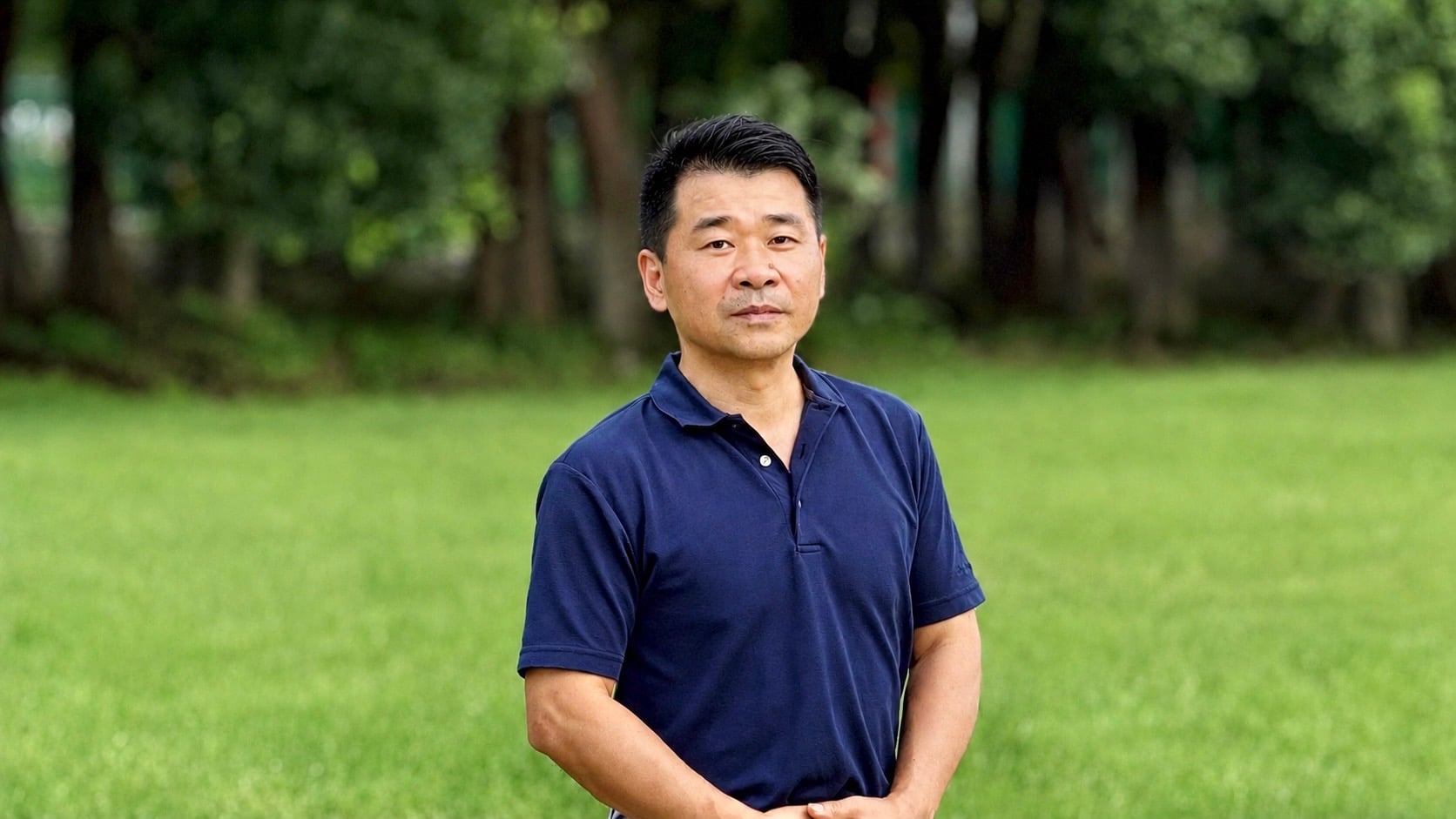 Liang Dong stands in a grassy field
