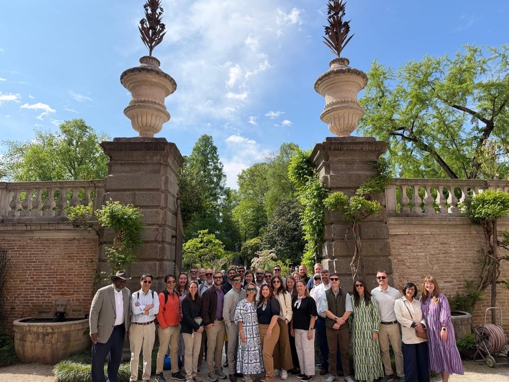 The AGL cohort stands in front of the stone entryway of the botanical garden at the University of Padua.