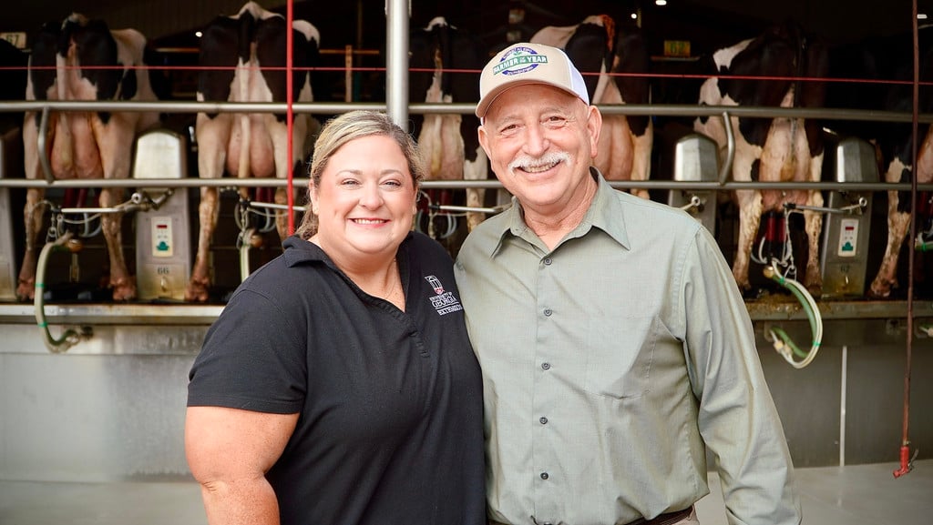UGA Extension agent Madison Luke stands with Pete Gelber in front of Holstein cows in the milking parlor at Barrington Dairy.
