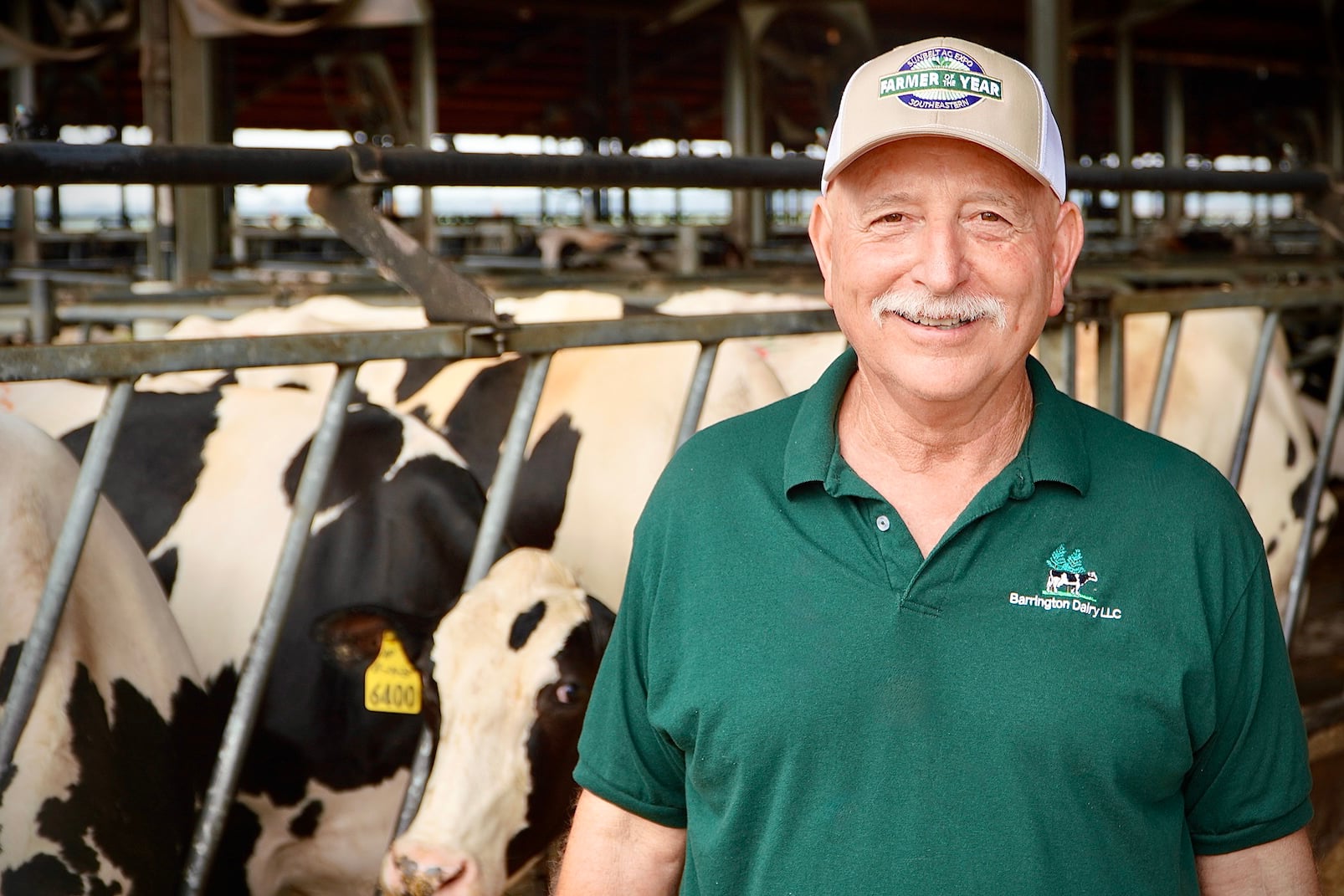 Dairy producer and 2026 Farmer of the year, Pete Gelber, standing in front of a stall with dairy cows in the background.