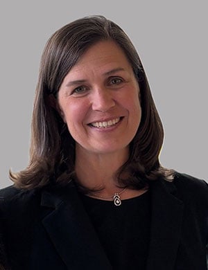 A smiling woman with shoulder length, straight brown hair and a black top. 